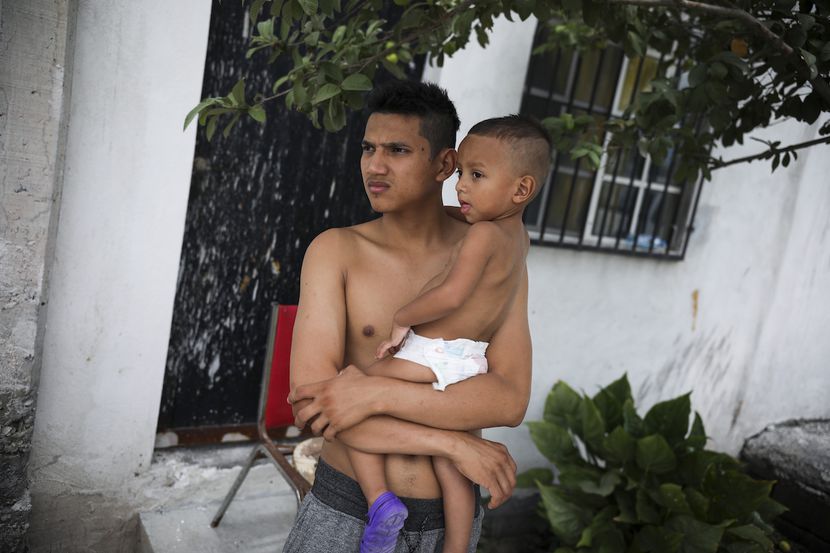 Gerardo, un migrante hondureño carga a su hijo Orlando, afuera de la iglesia Viento Recio en...
