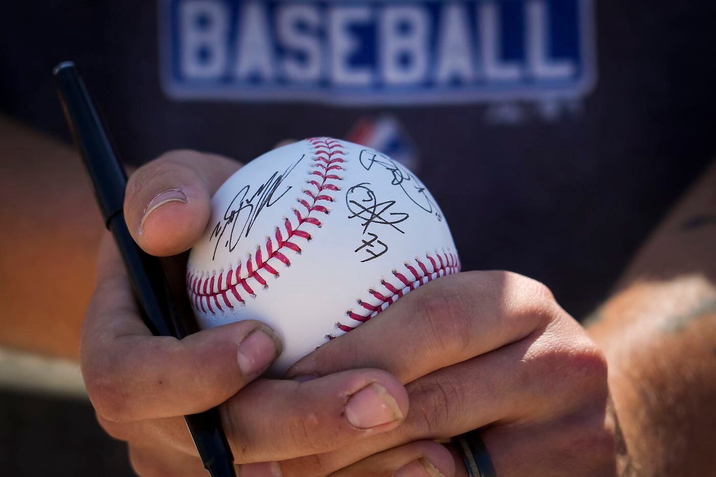 A fan holds a ball recently signed by Texas Rangers infielder Andy Ibáñez (77) while waiting...