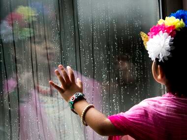 Marley Leyva, 4, watches rain roll down a window during the Frida Fest.