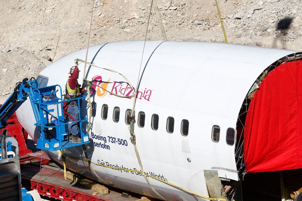A construction worker secures the cockpit and front section of an airplane before moving it...