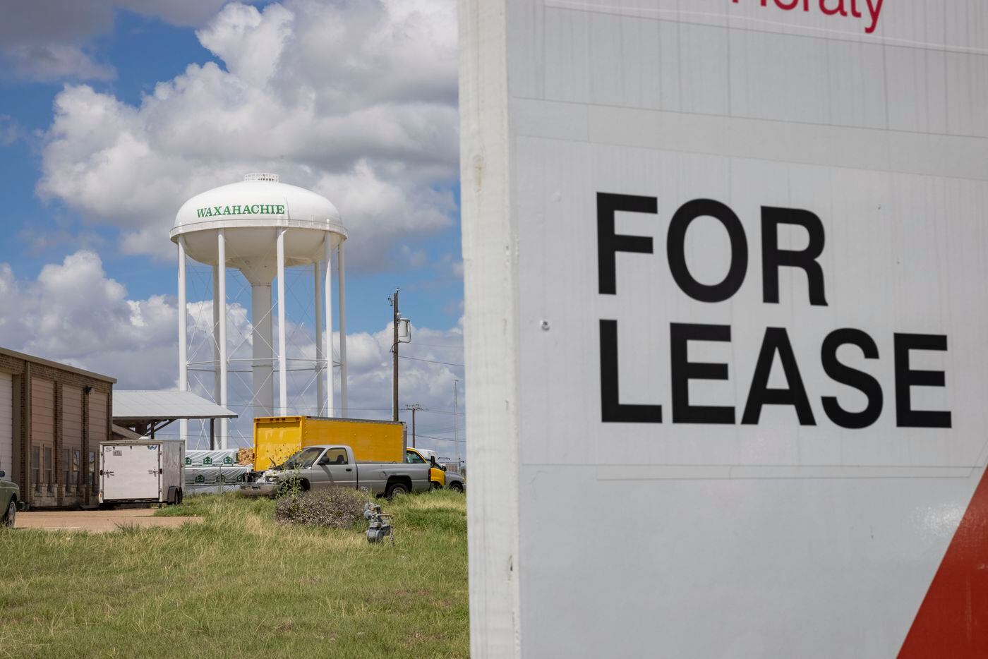 A Waxahachie water tower is seen behind a coming soon office for lease sign in Waxahachie.
