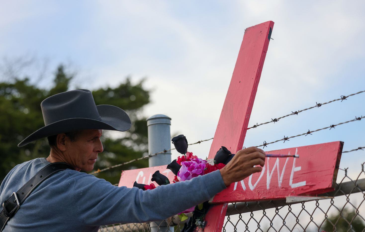 Artist Roberto Márquez paints the name of Curtis Rowe, one of three identified victims of...