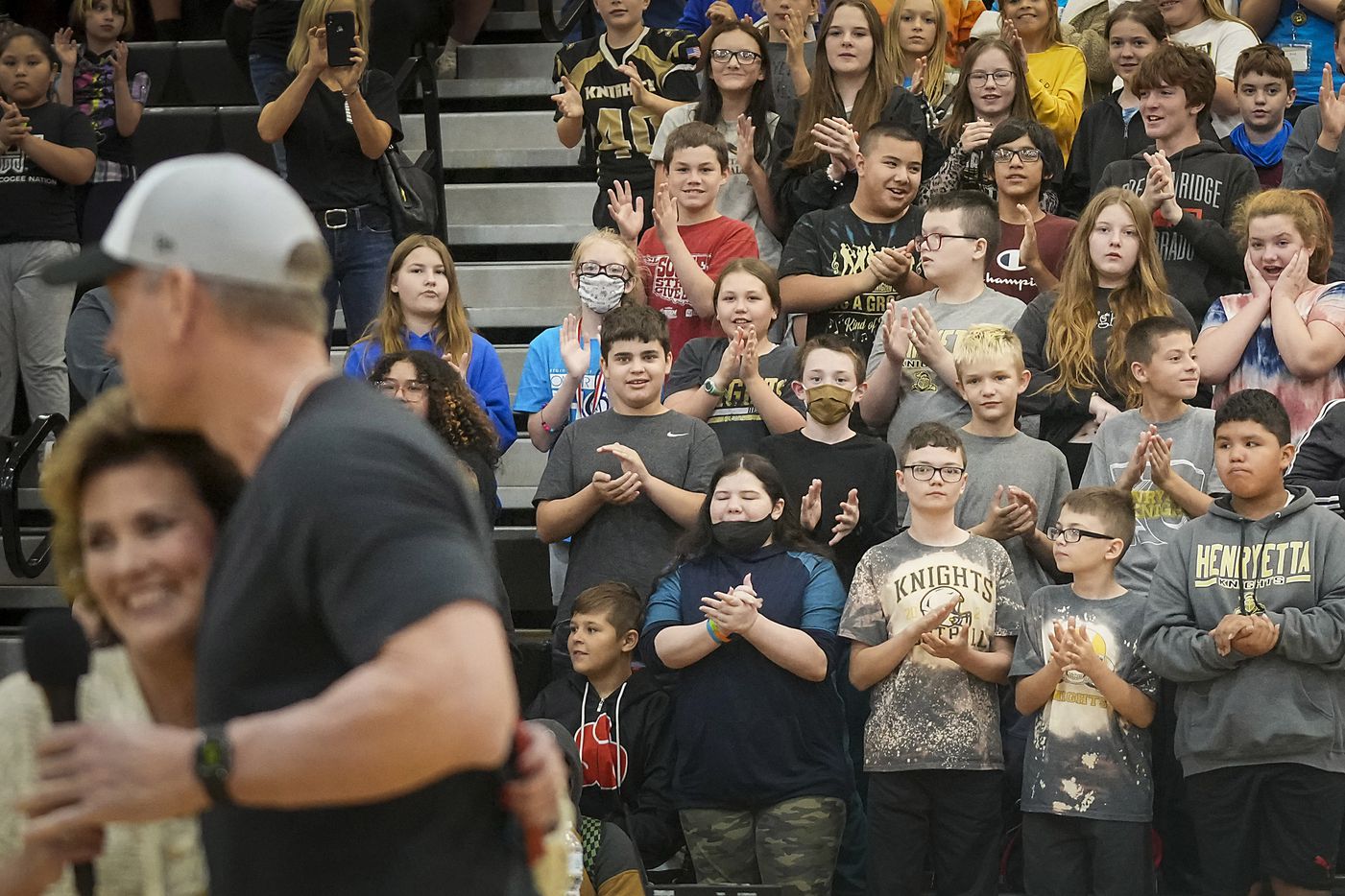 Elementary and middle school students applaud as Troy Aikman is introduced by mayor Jennifer Cummings Munholland as he arrives to surprise students during a pep rally.