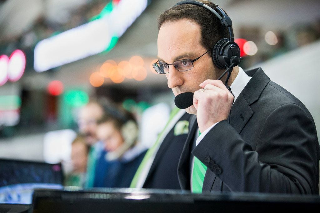 Josh Bogorad, a Dallas Stars play-by-play broadcaster, watches the hockey game between the...