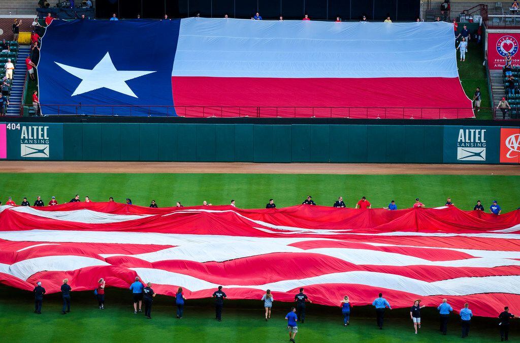 First responders from the Arlington police and fire departments unfurl large US and Texas flags at Globe Life Park before a game between the Texas Rangers and the Tampa Bay Rays on Wednesday, Sept. 11, 2019, in Arlington.
