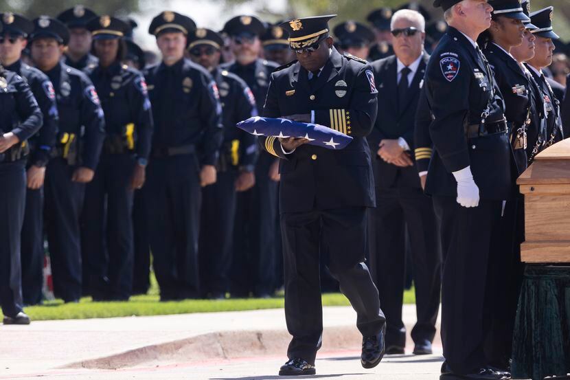 Arlington police Chief Al Jones carries the folded American flag to Lynette McMichael, the...