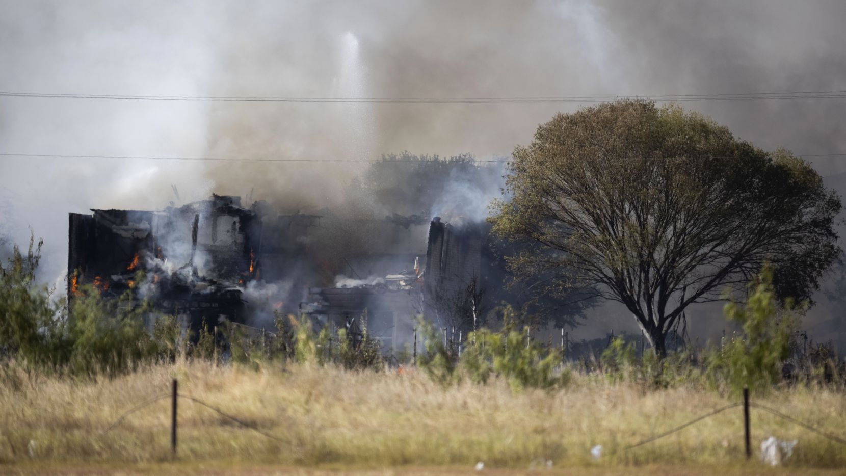 Smoke rises from the ashes after firefighters extinguished a large grass fire that spread...