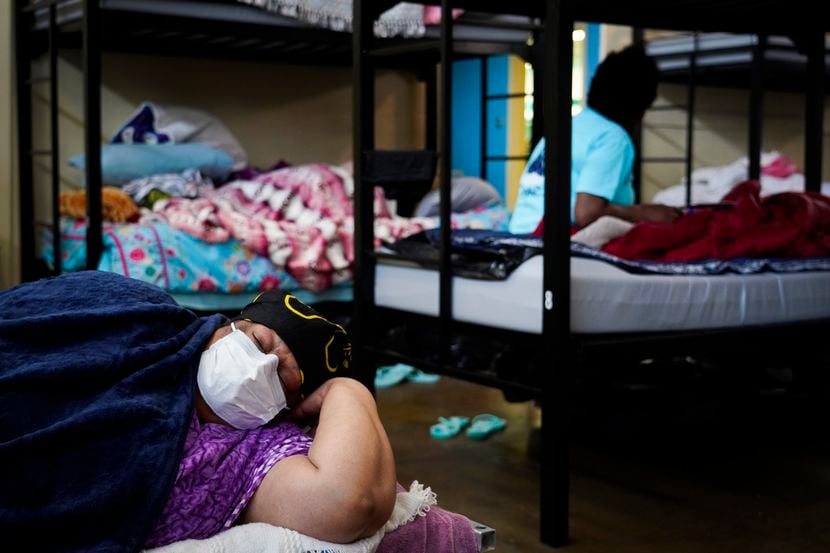 L. A. White wears a face mask as she rests in a bunk at Austin Street Center on Wednesday,...