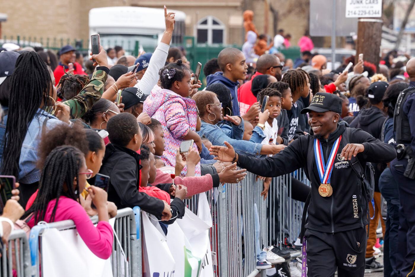 South Oak Cliff football player Jordan Mayes high-fives parade goers during the Martin...