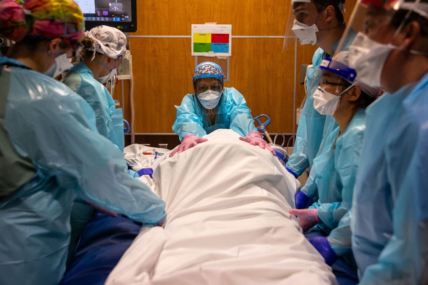 Rowley (right) assists Dr. Catherine Chen (second from right), respiratory therapist Ellen Tabor (center) and other Parkland medical staff as they prepare to turn an intubated COVID-19 patient to prone position.