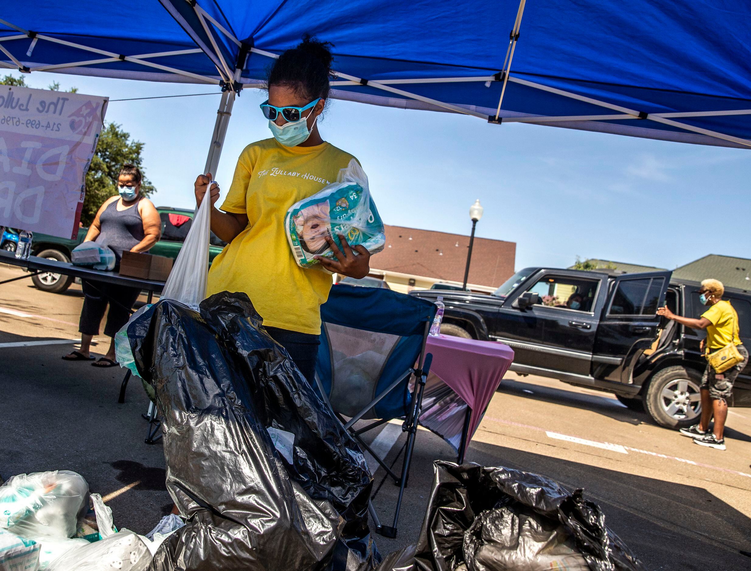 Volunteer Harmony Cornelius (center), 12, prepares diaper packages for families visiting a...