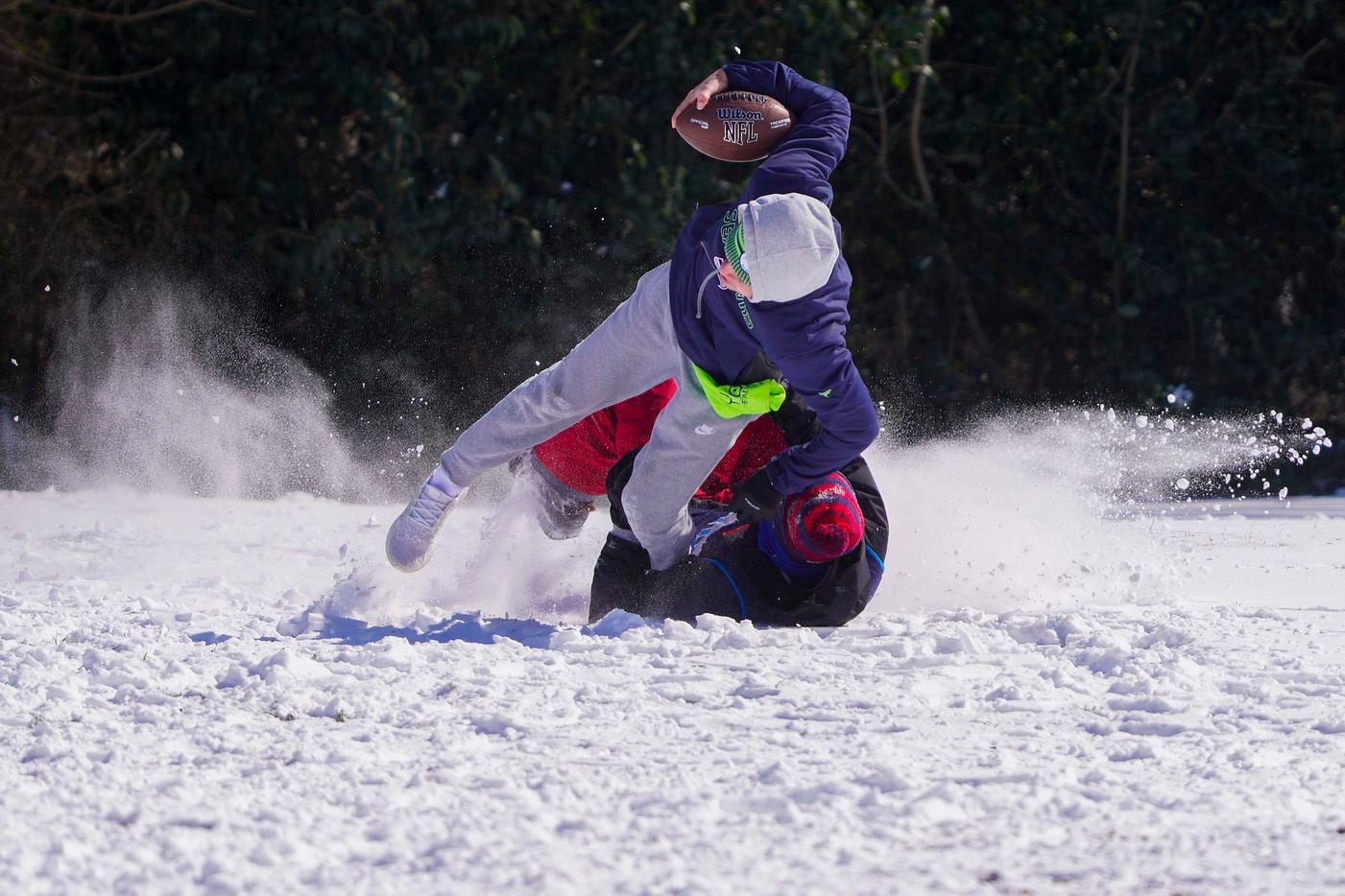 Andre Cavazos is brought down by Wesley Hart as they play football with other friends from J.J. Pearce High School at Prairie Creek Park after winter storm brought snow and freezing temperatures to North Texas on Monday, Feb. 15, 2021, in Richardson.  (Smiley N. Pool/The Dallas Morning News)