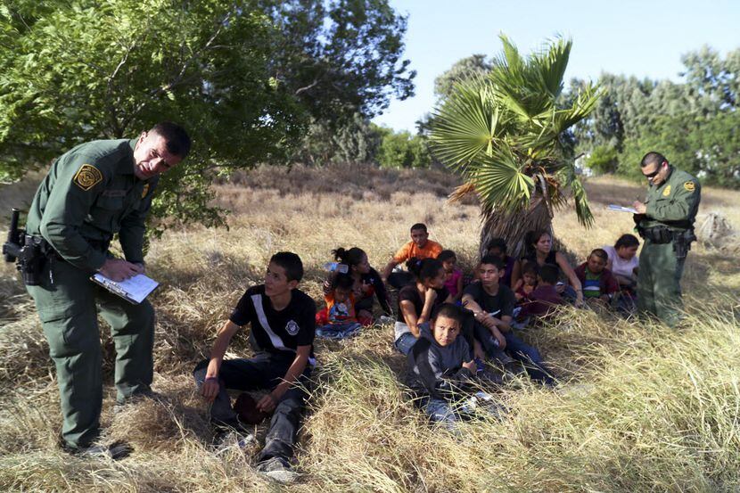 Border Patrol agents process a group of 22 migrants, mostly women and children from Honduras...