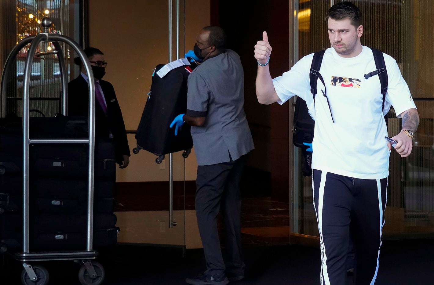 Dallas Mavericks guard Luka Doncic gives a thumbs up to fans as the team leaves their hotel...