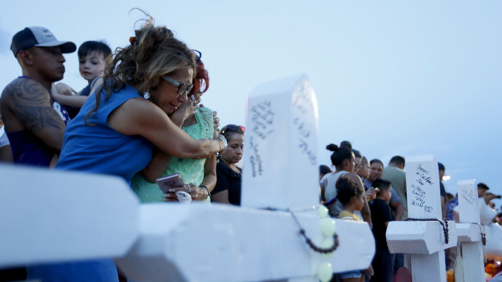 Rebecca Najera hugs Elsa Escobar on Aug. 5 as they joined other mourners gathered beside crosses representing the victims of a shooting at a Walmart in El Paso.
