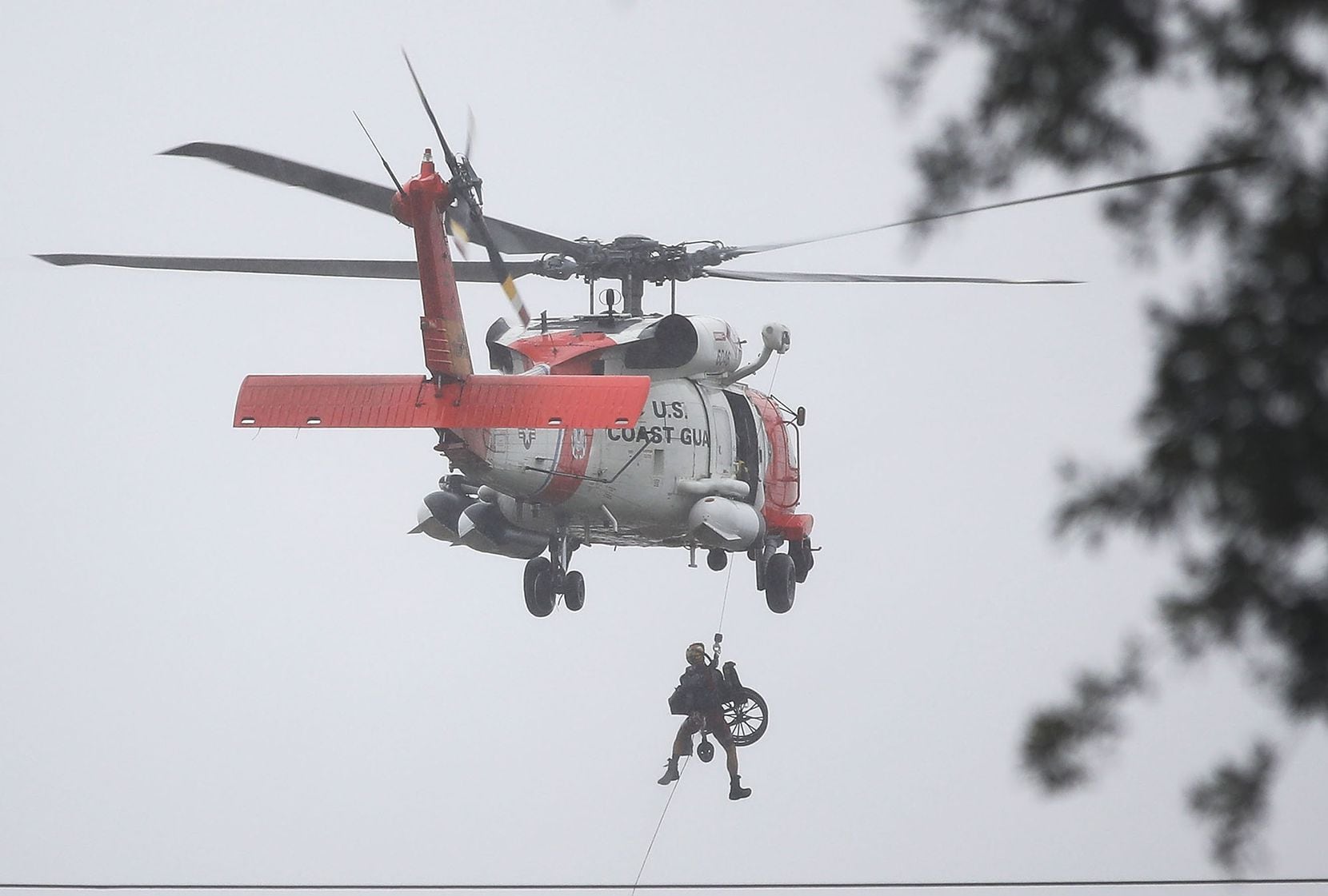 A Coast Guard helicopter hoists a wheel chair on board after lifting a person to safety ...
