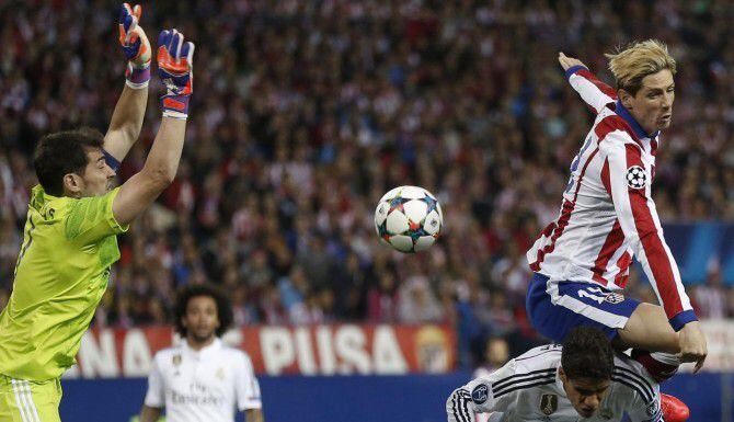 Iker Casillas (der.) del Real Madrid intuye un remate de Fernando Torres, del Atlético de...