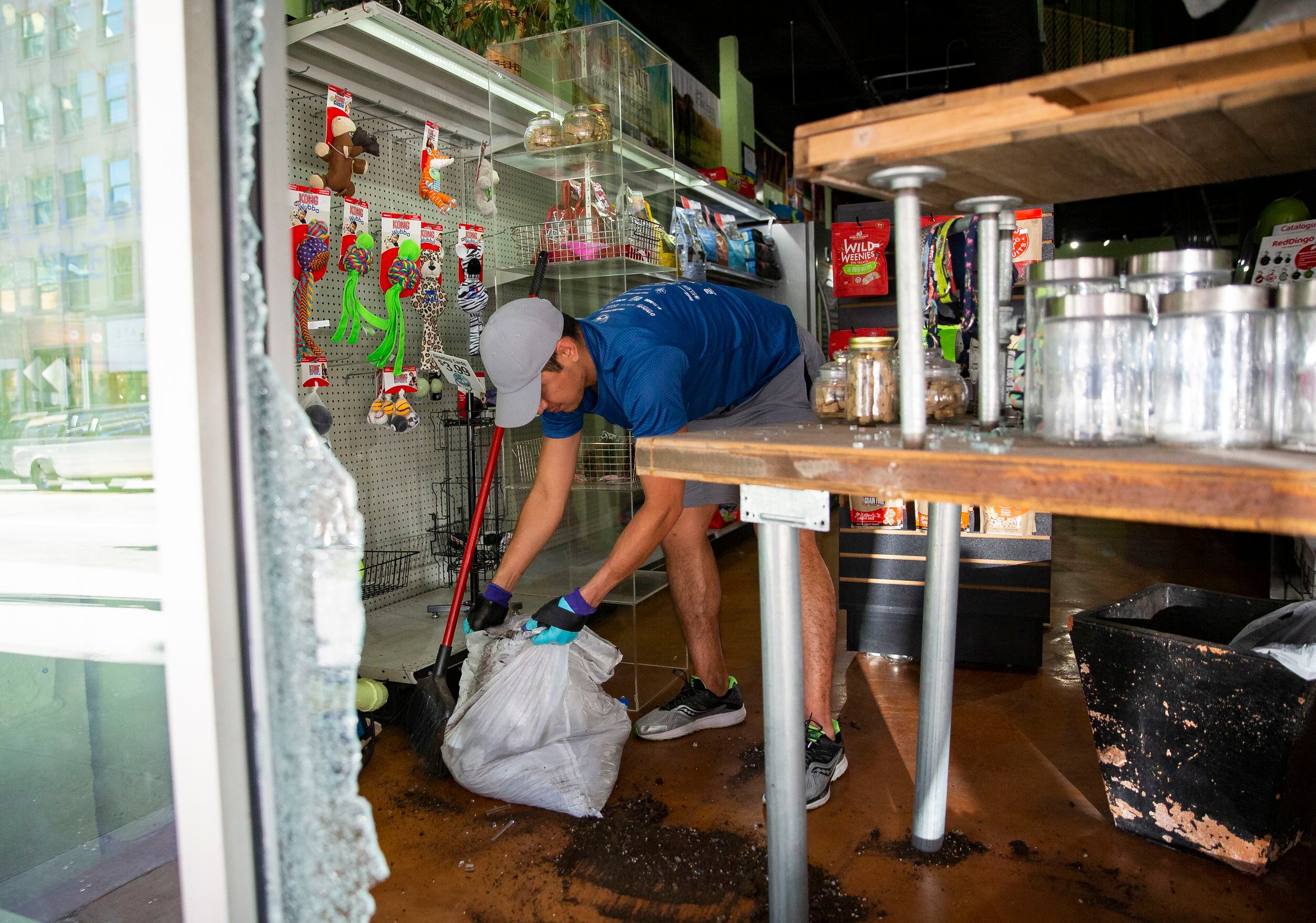 Downtown Pawz co-owner Jonathan Bustos cleans up inside the shop after being hit during last...