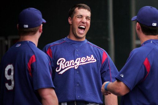Rangers Mark Teixeira laughs with teammates Hank Blalock, left, and Michael Young, right, as...