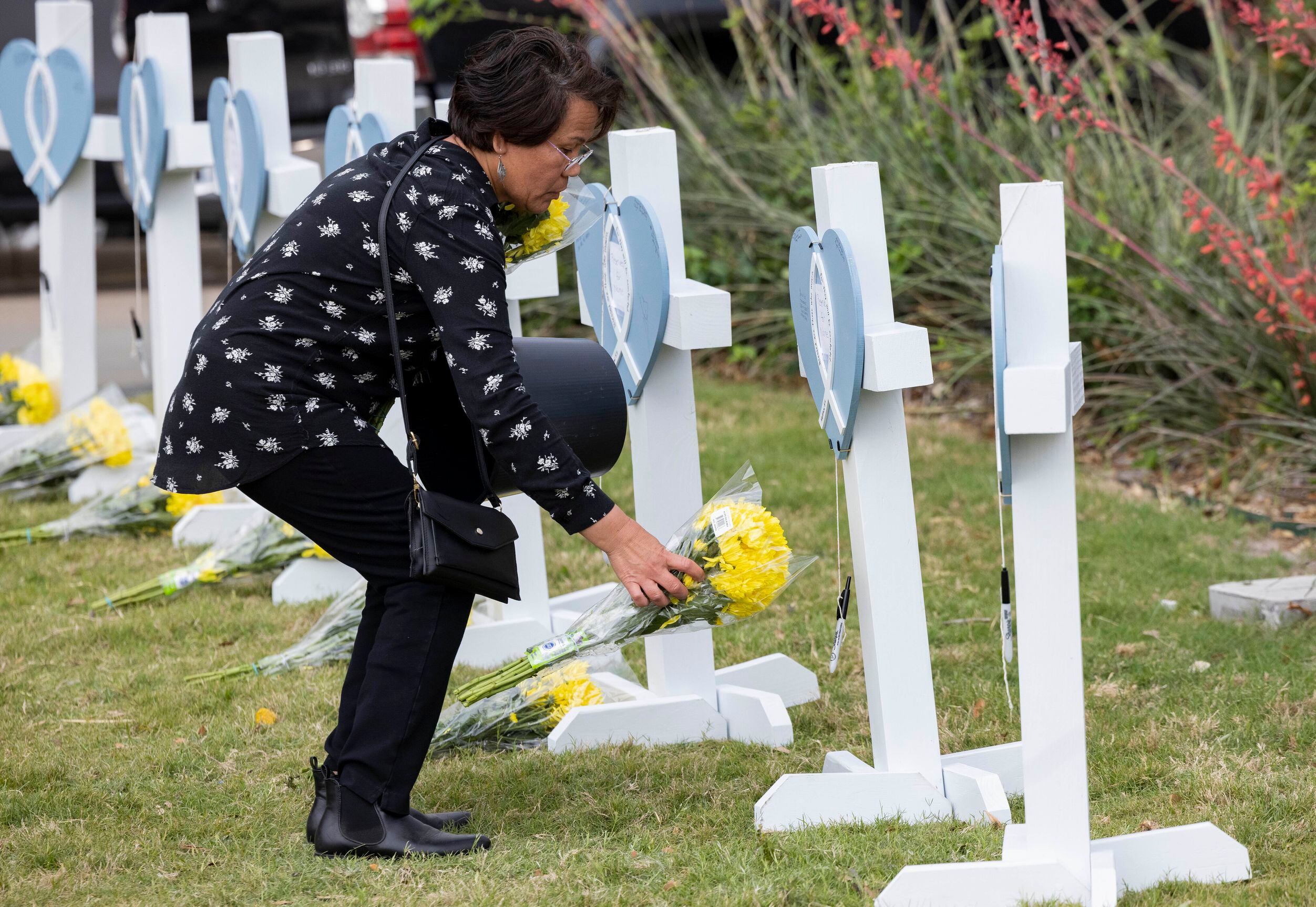 Gina Bennet leaves yellow flowers at the memorial outside the mall honoring the victims of a...