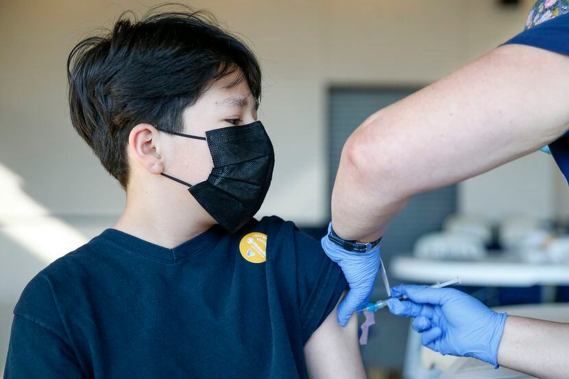 Jancarlo Aguado, 13, of Dallas receives the Pfizer vaccine from staff of Methodist Health...