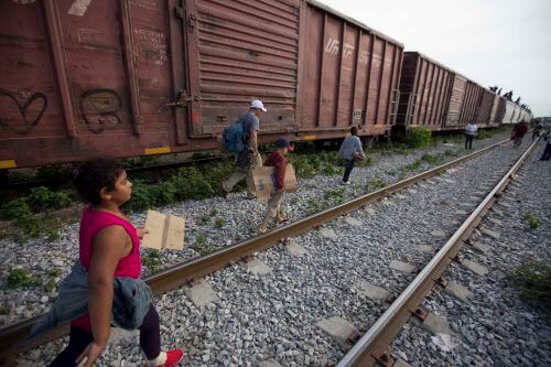 En esta foto de archivo, unos migrantes caminan por las vías tras bajarse de un tren en su...