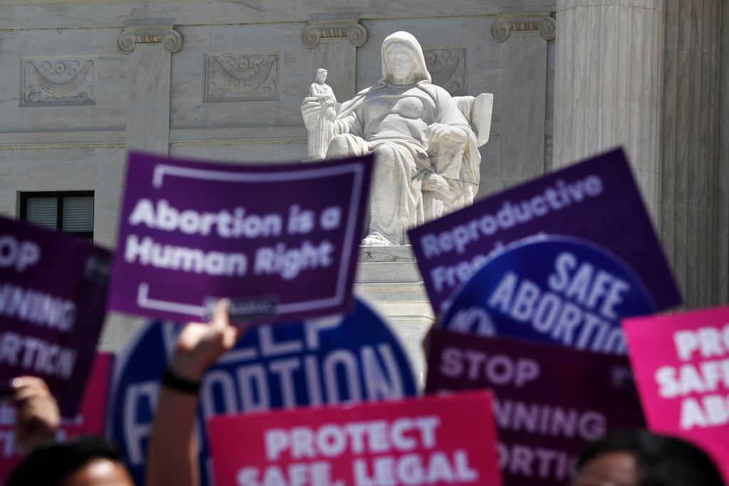 People hold up signs in favor of legal abortion during a protest against abortion bans,...