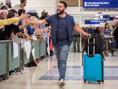 Traveler Alex Galindo high-fives protestors at DFW International Airport holds signs in...