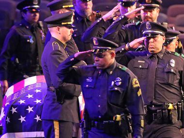 Dallas police officers salute their fallen comrade during the uniformed officers pass-by at...