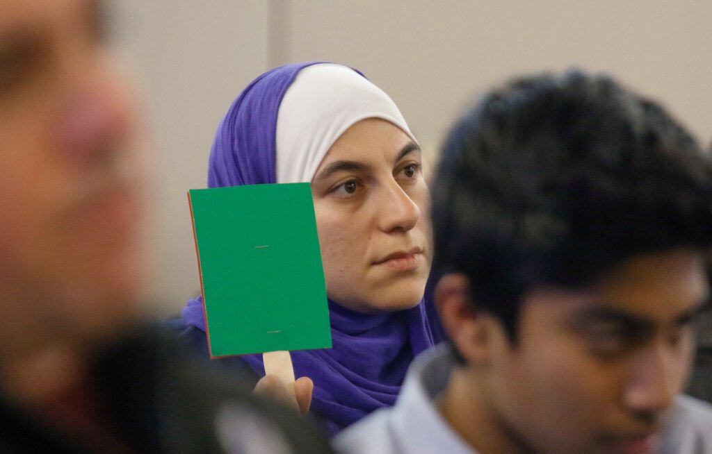 Alia Shakir holds up a green sign in solidarity with one of the speakers at the McKinney ISD...