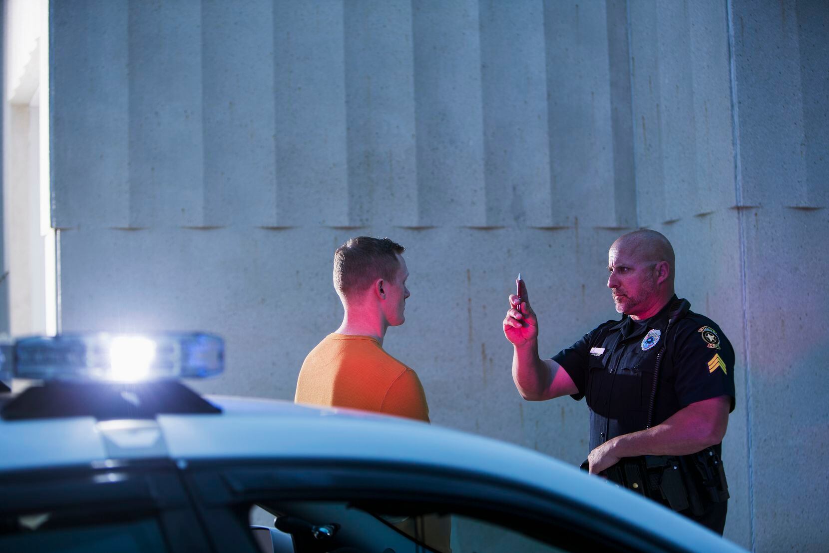 Police officer giving sobriety test to young man to see if he is driving under the influence...