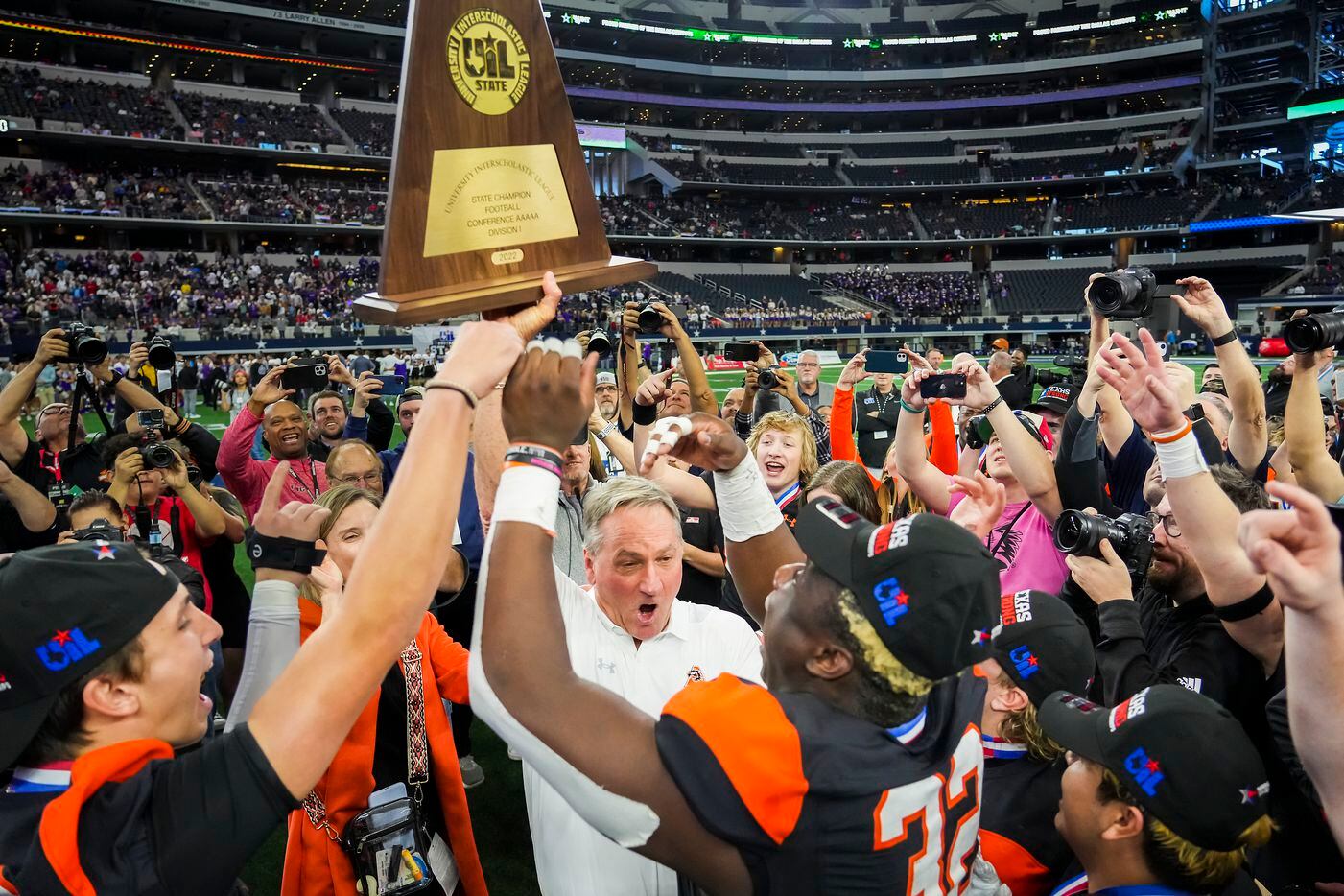 Aledo head coach Tim Buchanan lifts the championship trophy with his players as they...