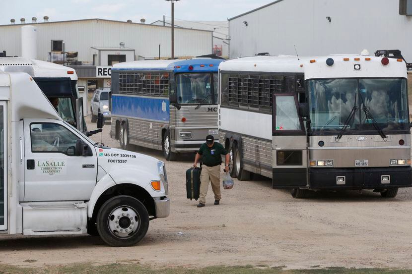 Los autobuses llenos con empleados detenidos salen después de que el Servicio de Inmigración...
