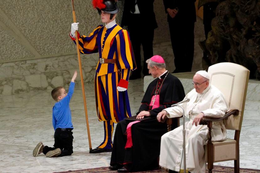Un niño juega con un miembro de la guardia suiza en la sala de audiencias Pablo VI, el...