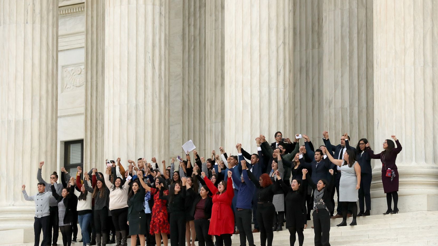 People raise their fists in the air and cheer Tuesday on the steps of the U.S. Supreme Court...
