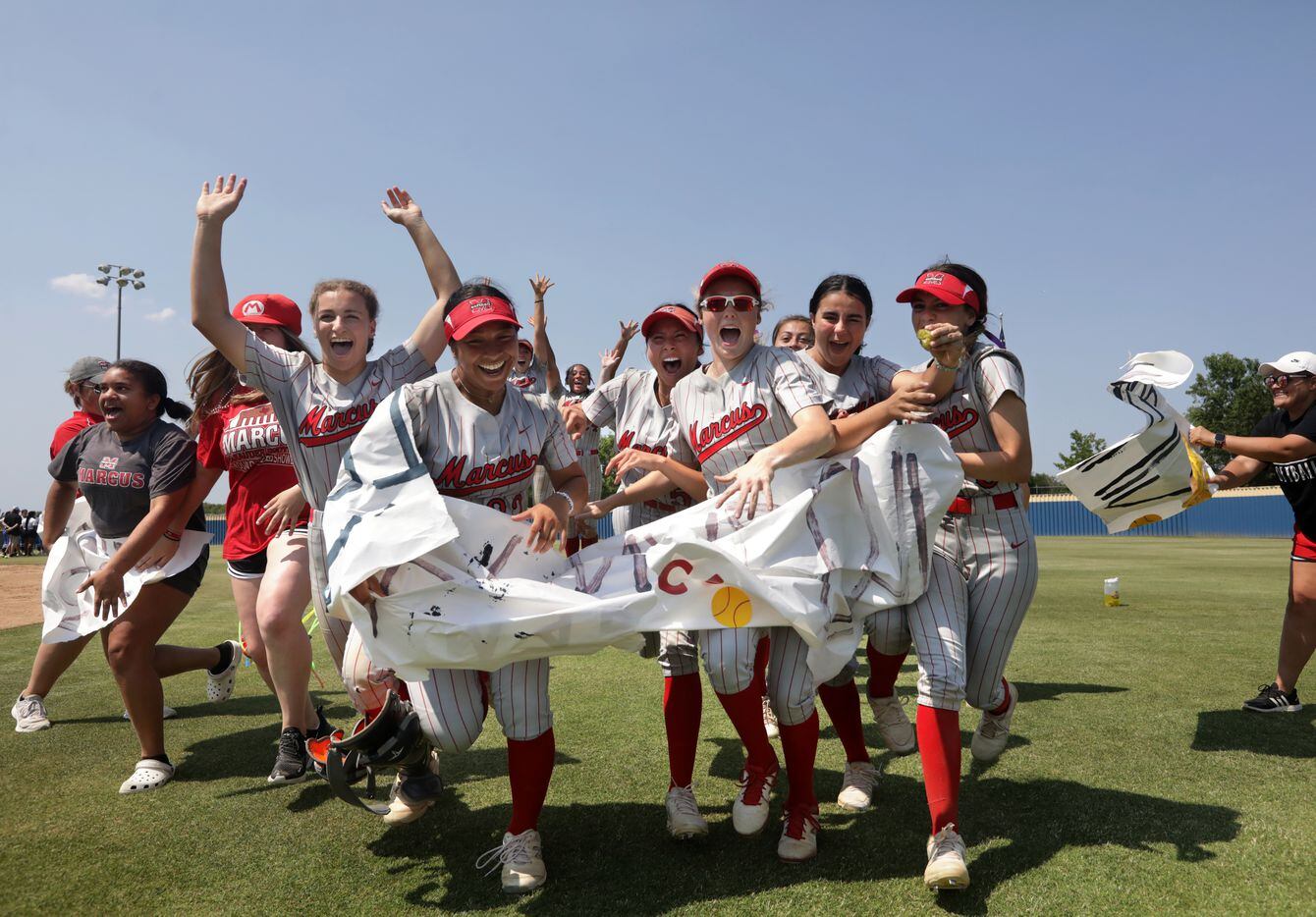 The Flower Mound Marcus High School players celebrate after winning a softball playoff game...