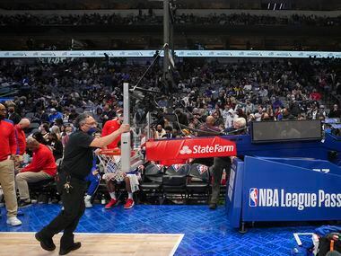 Officials move in a new basket during the first half of an NBA basketball game between the...