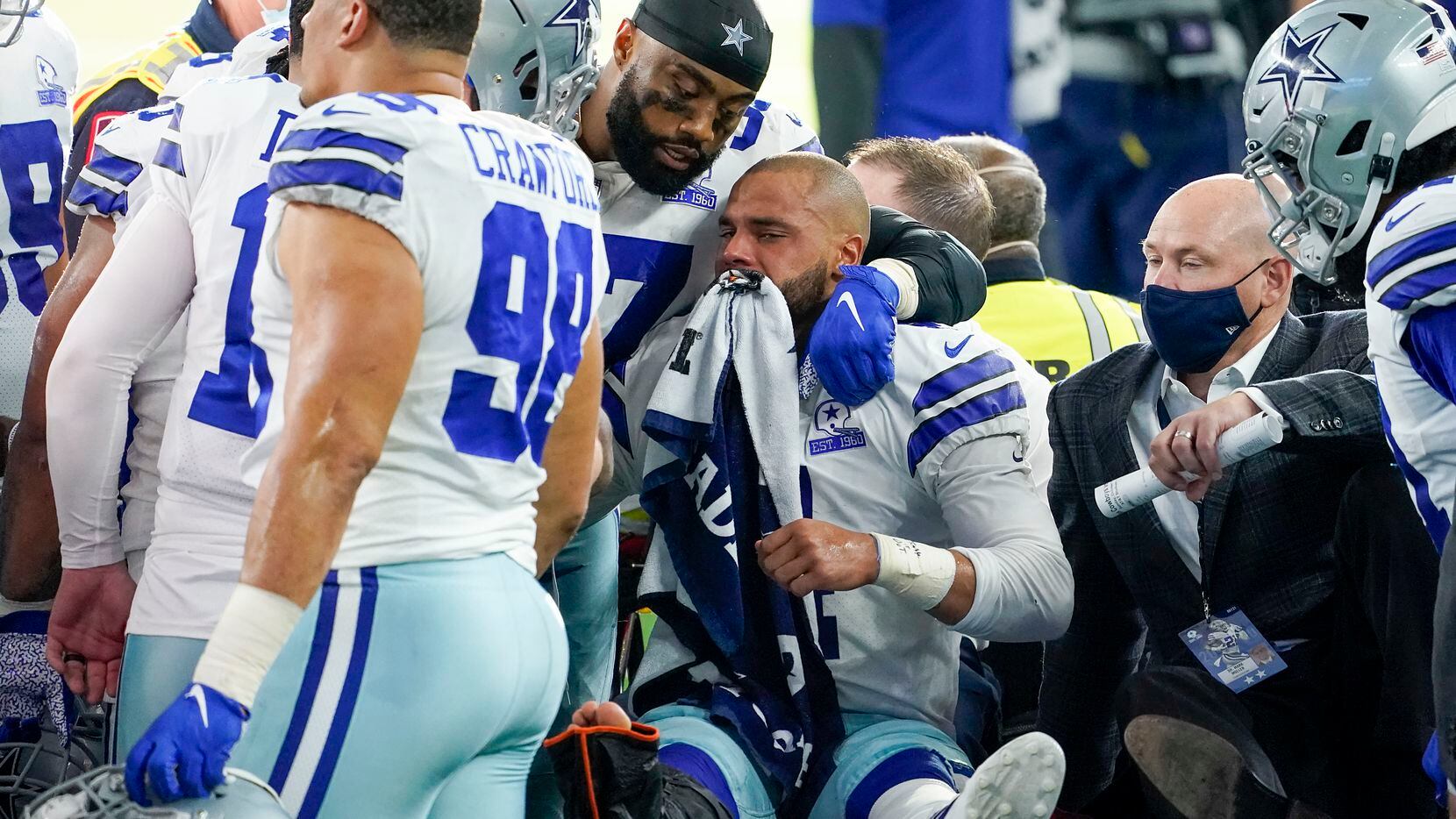 Dallas Cowboys quarterback Dak Prescott lis consoled by teammates as he lea...
