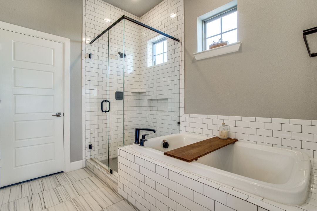 The glass tile and soaking tub have subway tile details.