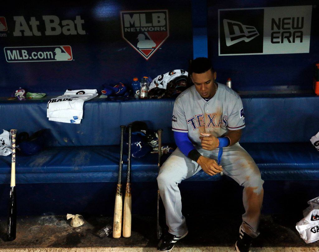 Texas Rangers left fielder Carlos Gomez (14) unwraps his wrists i the dugout after losing...