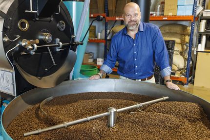 Founder and CEO Chris Parvin stands over freshly roasted coffee beans at White Rhino...