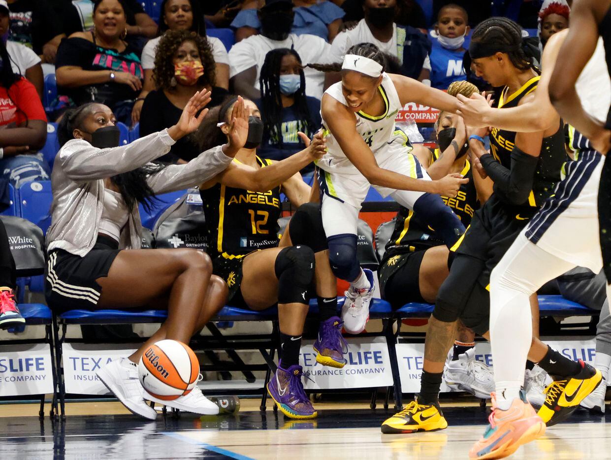 Dallas Wings guard Moriah Jefferson (4) ends up on the Los Angeles Sparks bench as she is fouled by Los Angeles Sparks guard Brittney Sykes, right, as they attempted to go for a loose ball during the second half of a WNBA basketball game in Arlington, Texas on Sunday, Sept. 19, 2021. (Michael Ainsworth/Special Contributor)