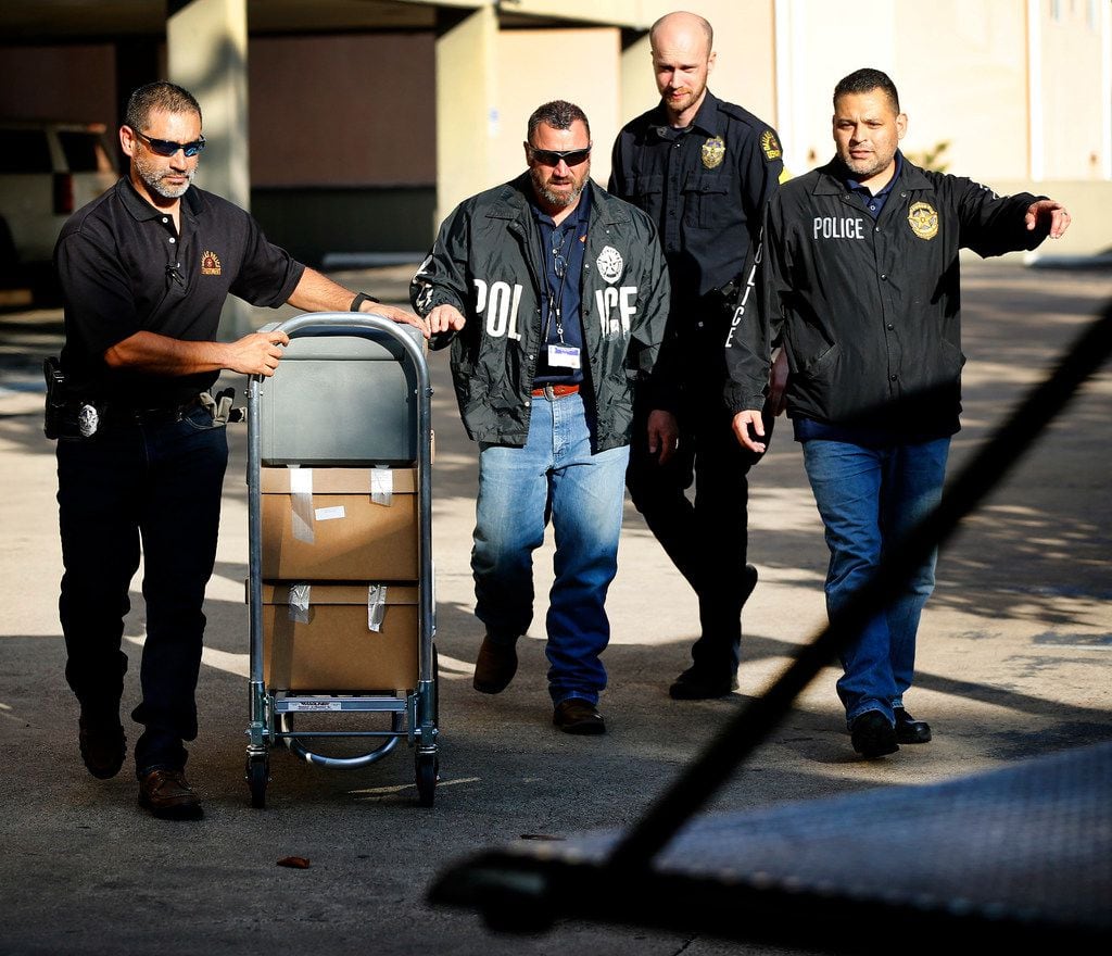 Dallas police officials cart out boxes from a raid on the Catholic Diocese of Dallas,...