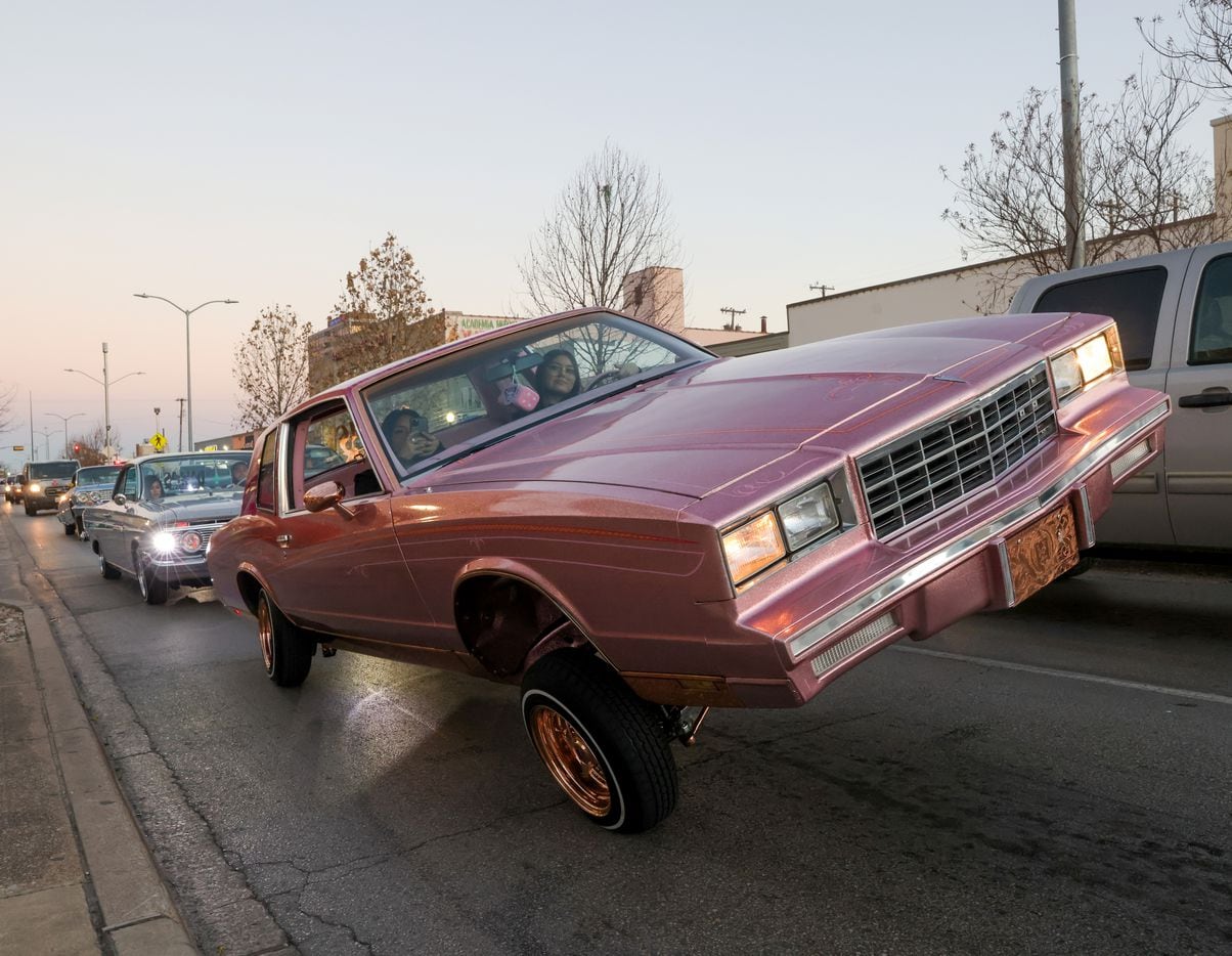 Mercedes Mata (right) raises her car as she and other Dallas Lowriders members cruise from...
