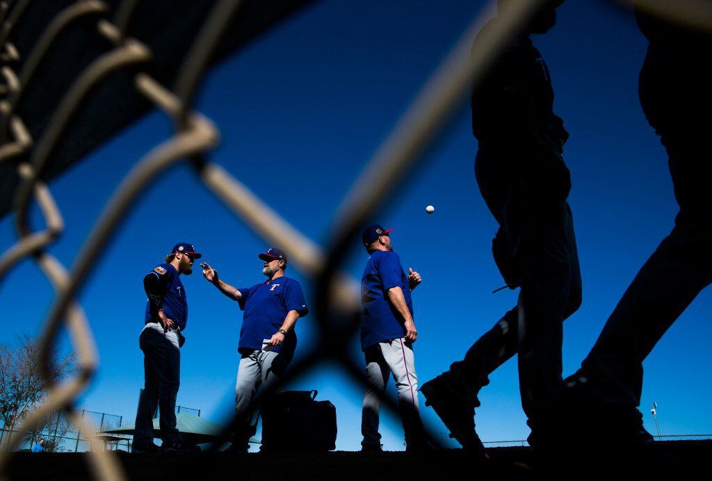 Texas Rangers starting pitcher Andrew Cashner (54, far left) talks to pitching coach Doug Brocail (46) while bullpen coach Brad Holman (40) tosses a ball and other pitchers walk to their next drill during a spring training workout at the team's training facility on Tuesday, February 15, 2017 in Surprise, Arizona. (Ashley Landis/The Dallas Morning News)