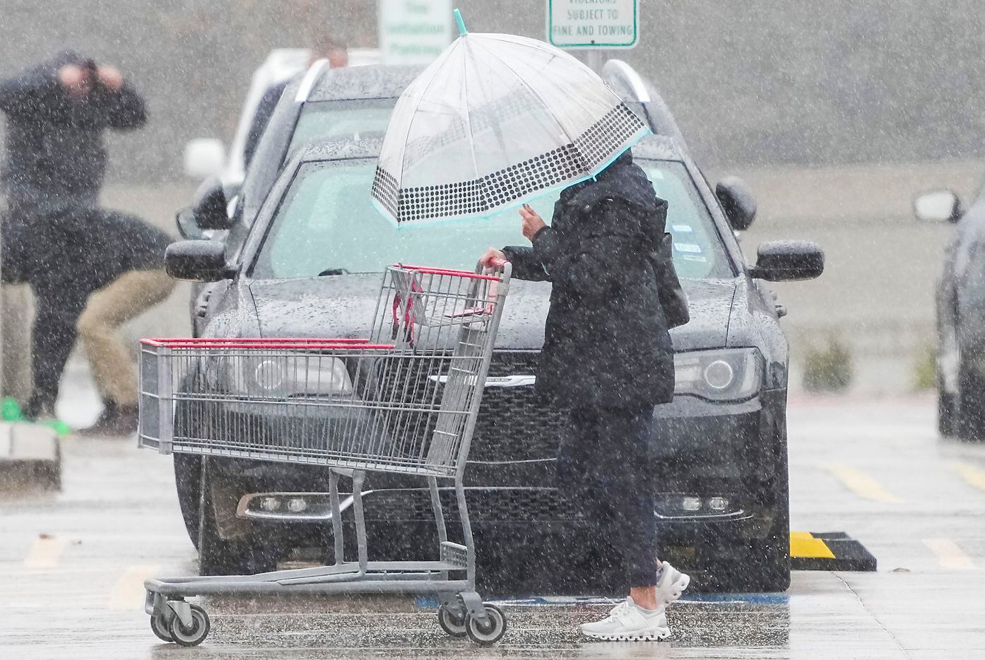 المتسوقون في متجر Costco في بلانو يتنقلون تحت المطر البارد في ساحة انتظار السيارات يوم الاثنين ، يناير ....