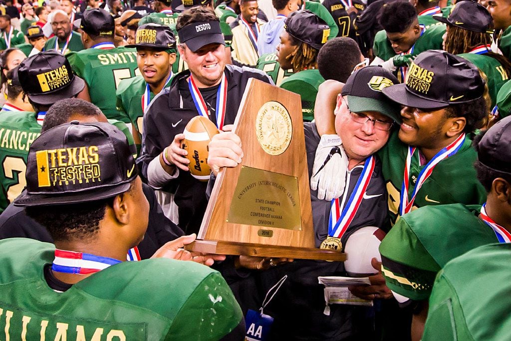 DeSoto head coach Todd Peterman clutches the championship trophy as he celebrates with his...