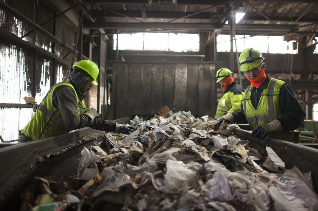  Workers remove contaminants from a stream of recyclables at the Waste Management facility...