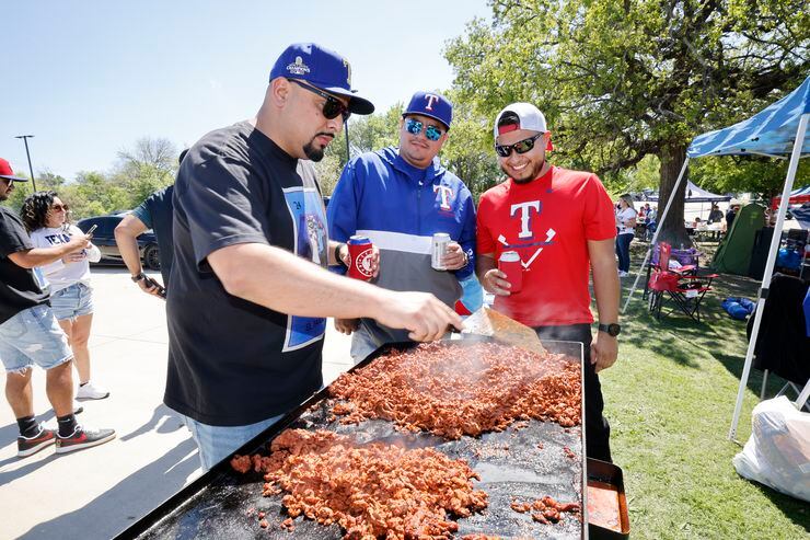 Texas Rangers fans Sergio Erazo of Arlington (from left) cooked while tailgating with...
