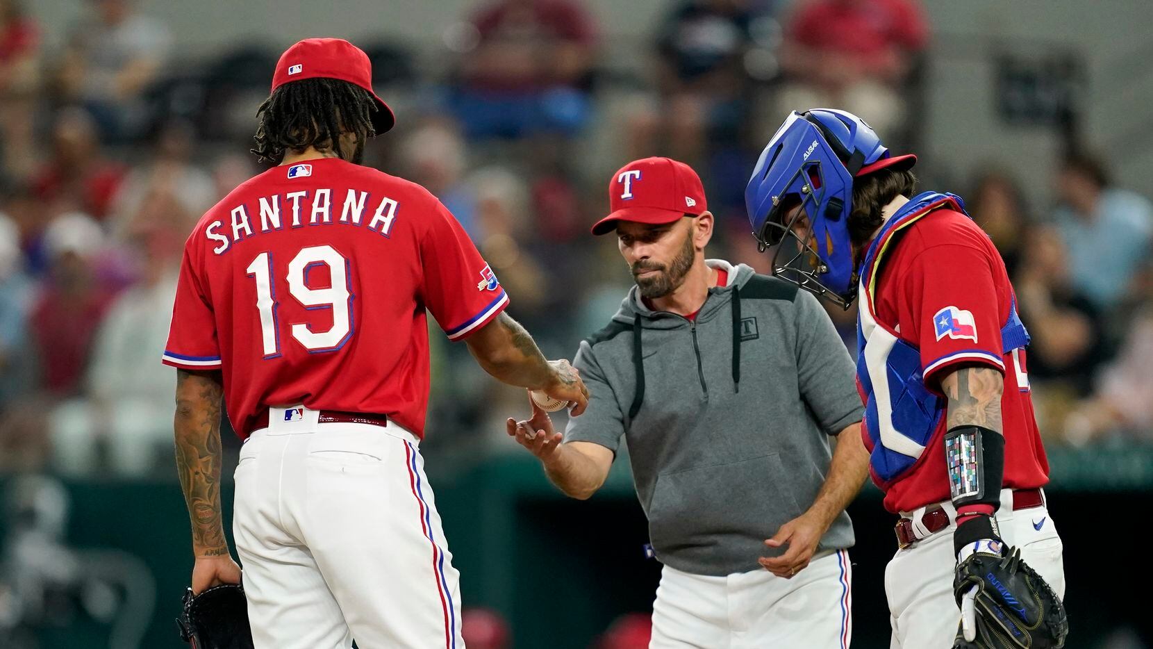 Texas Rangers' Dennis Santana (19) turns the ball over to manager Chris Woodward, center, as...